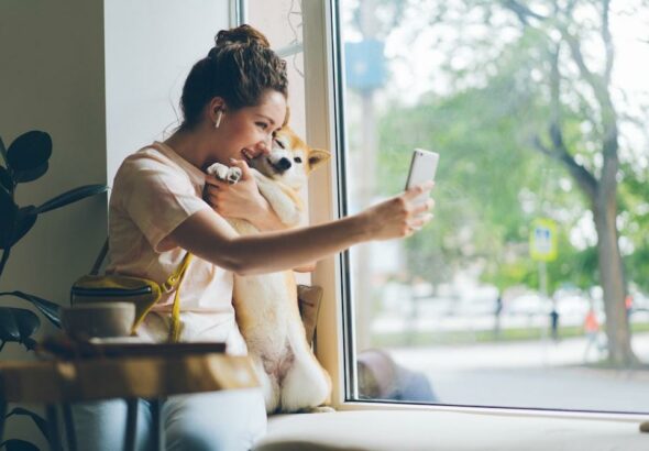 a woman looking at her cell phone while holding a dog